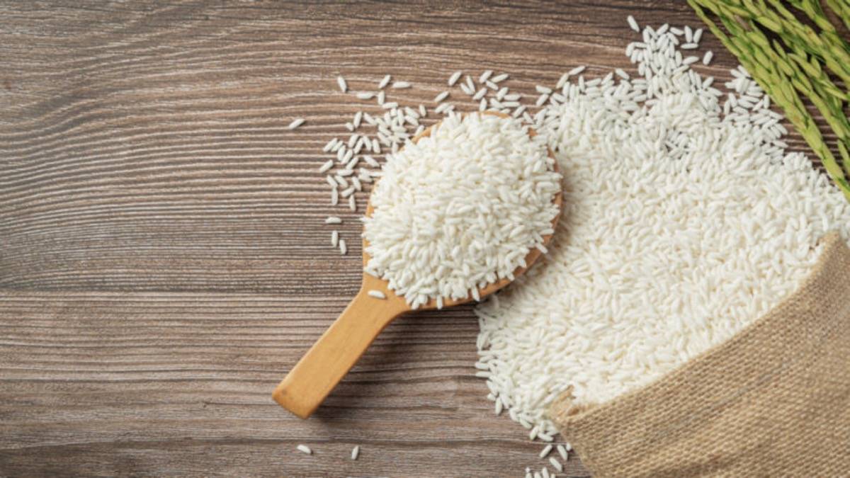 A Sack Of Rice With Rice On Wooden Spoon And Rice Plant